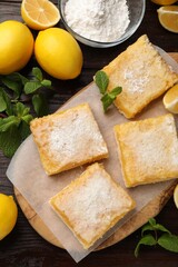 Tasty lemon bars with powdered sugar and mint on wooden table, flat lay