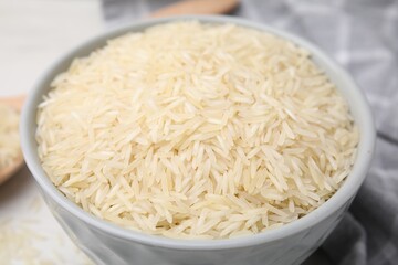 Raw rice in bowl on table, closeup