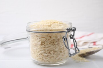 Raw rice in glass jar on white table, closeup