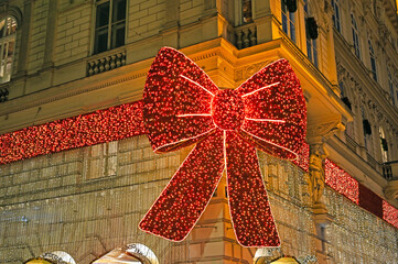 Ornamental garland red bow on a building facade in Vienna city center at night