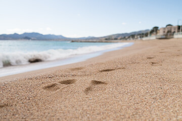 Footsteps on a sand beach of South France during spring with sea waves