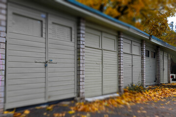 Car garage facade with wooden plank door and yellow leaves on the ground