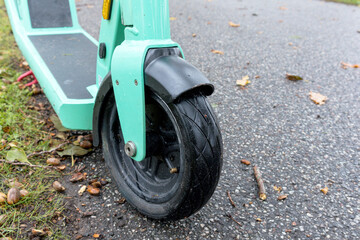 .A green colored scooter with a small front wheel