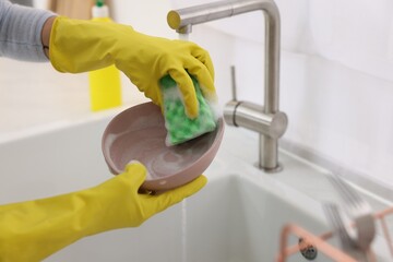 Woman washing plate above sink in modern kitchen, closeup. Space for text