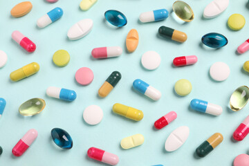 Many different pills on light turquoise background, flat lay