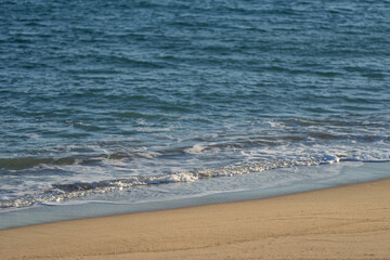 Waves rolling on a sandy beach on a sunny day