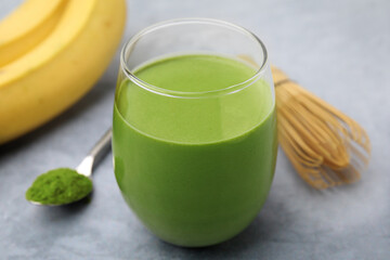 Glass of tasty matcha smoothie on light grey table, closeup
