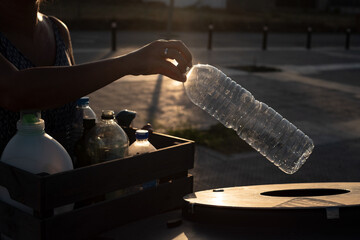 A woman inserts plastic bottles into the recycling container