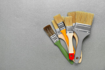Many different paint brushes on grey background, flat lay. Space for text