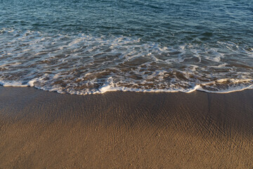 Waves rolling on a sandy beach on a sunny day