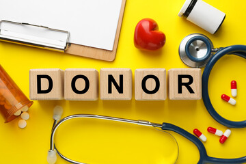 Flat lay composition with wooden cubes with word Donor on yellow background