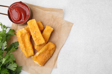 Tasty fried mozzarella sticks served with parsley and ketchup on white table, flat lay. Space for...