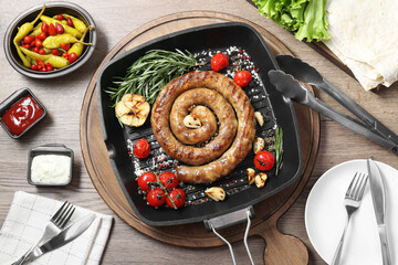 Delicious homemade sausage with garlic, tomatoes, rosemary and spices served on wooden table, flat lay