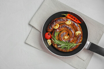 Delicious homemade sausage with garlic, tomato, rosemary and chili in frying pan on white table, top view. Space for text