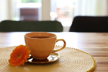 Cup of delicious chamomile tea and fresh calendula flower on wooden table in room, space for text