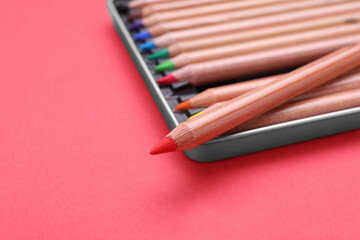 Naklejka premium Box with many colorful pastel pencils on red background, closeup and space for text. Drawing supplies