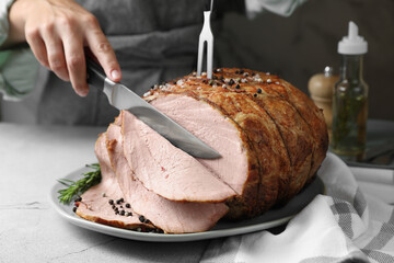 Woman cutting delicious baked ham at light grey table, closeup - Powered by Adobe