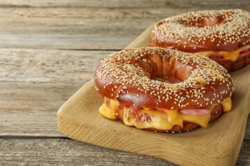 Delicious bagels with ham and cheese on wooden table, space for text