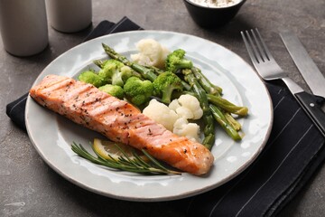 Healthy meal. Piece of grilled salmon, vegetables, asparagus and rosemary served on grey textured table, closeup