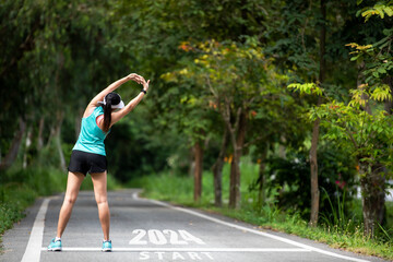 The start into the new year 2024. Start up of runner woman running on nature race track go to Goal...