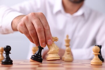 Man moving chess pieces on checkerboard, closeup