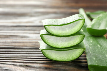 Fresh aloe vera pieces on wooden table, closeup. Space for text