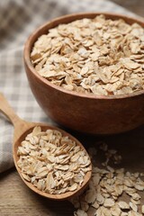 Bowl and spoon with oatmeal on wooden table, closeup