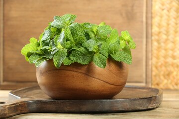 Bowl with fresh green mint leaves on wooden table