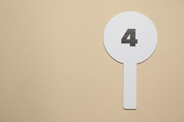 Auction paddle with number 4 on beige background, top view. Space for text