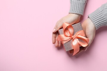 Christmas present. Woman holding gift box on pink background, top view. Space for text