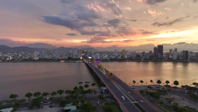 Da Nang, Vietnam - Aerial drone video of cars on the iconic Dragon Bridge in downtown Da Nang spanning the Han River at sunset