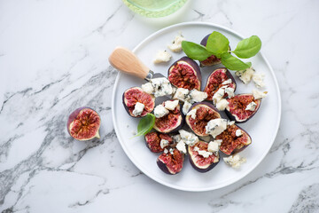 Plate with fresh fig fruits and blue cheese on a white marble background, horizontal shot with space, flat lay