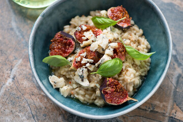 Risotto with fig fruits, blue cheese and basil leaves served in a green bowl, middle close-up, horizontal shot