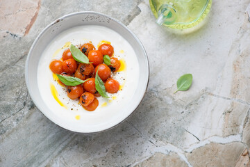 Bowl of tirokafteri or greek feta dip sauce with tomatoes, top view on a grey granite background, horizontal shot, copy space