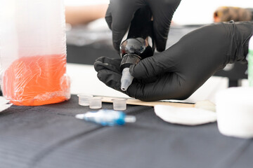 person holds a black bottle and pours ink into small caps