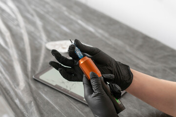 Naklejka premium a professional tattoo artist holding new machine in the studio