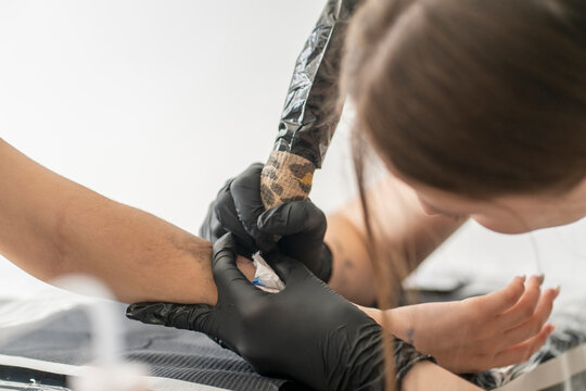master tattooist makes a tattoo on the skin of the hand client girl in a workshop with special equipment.