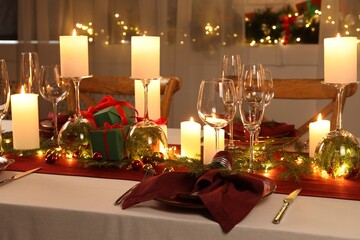 Christmas table setting with burning candles and festive decor
