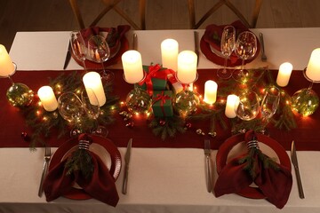 Christmas table setting with burning candles and festive decor, above view