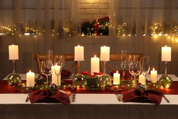 Christmas table setting with burning candles and festive decor