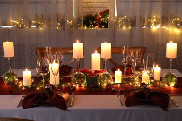 Christmas table setting with burning candles and festive decor