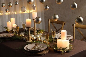 Christmas table setting with burning candles and festive decor