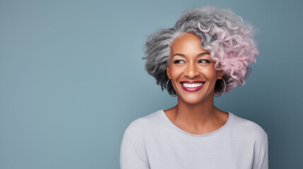 Radiant african american woman with silver and pink hair smiling joyfully on a blue background