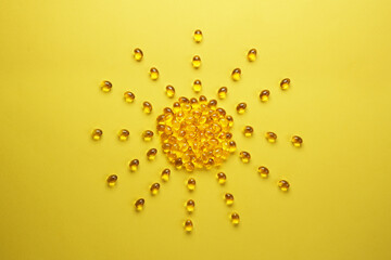 Pills of vitamin D3 in a shape of sun on yellow background. Top view, flat lay. Concept of nutritional supplement and health.  Creative composition.