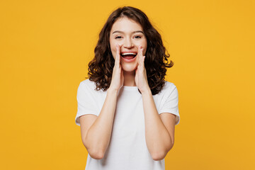 Young promoter fun woman she wear white blank t-shirt casual clothes scream sharing hot news about sales discount with hands near mouth isolated on plain yellow orange background. Lifestyle concept.