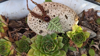 Ornament of green and brown ropes with a brown stone in the center on black