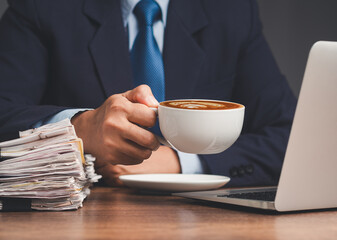 Businessman holding a cup of coffee while working at a desk.