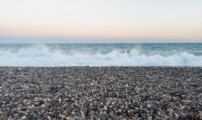 Sea wave, pebble coast and sky horizon in evening