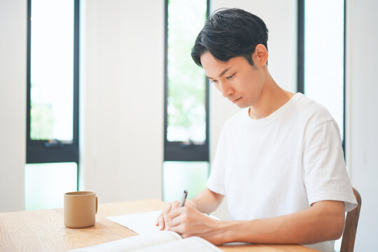 自宅のリビングで資格取得のために勉強する若い男性