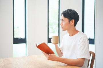 自宅のリビングで読書をする若い男性